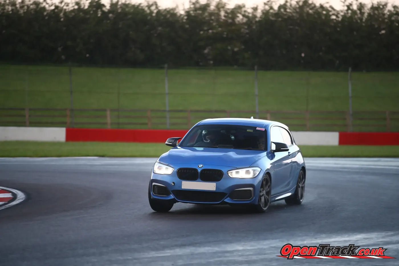 Blue BMW hatchback cornering on a damp track day